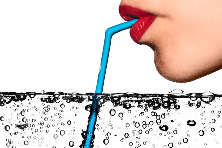 Woman drinking seltzer with a Koffie straw.